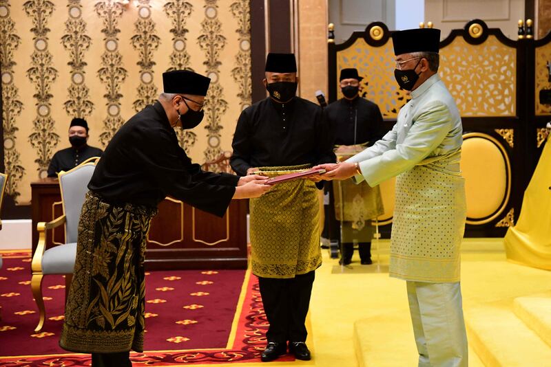 Malaysia's incoming Prime Minister Ismail Sabri Yaakob (left) receives documents from King Sultan Abdullah Sultan Ahmad Shah before taking the oath as the country's new leader at the National Palace in Kuala Lumpur, on August 21. Malaysia's Department of Information  /  AFP
