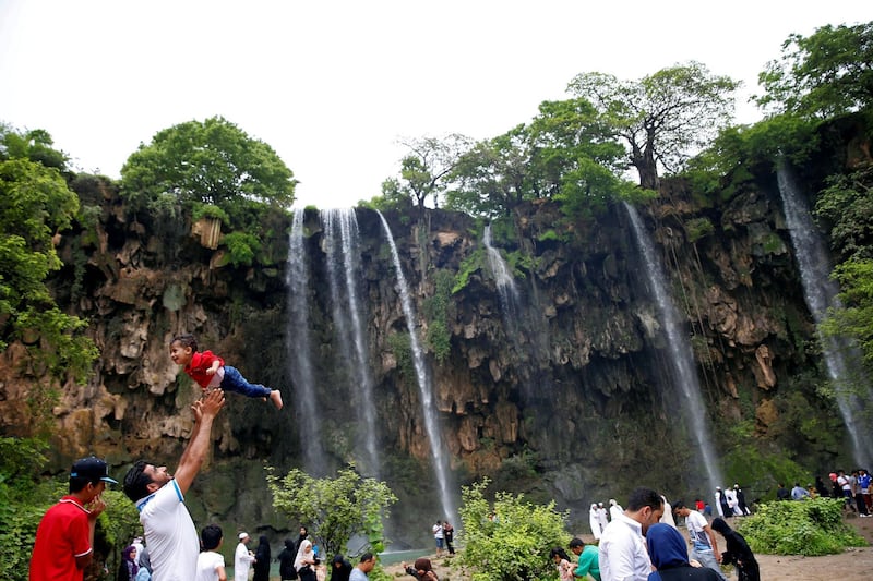 A tourist lifts up a boy as they visit waterfalls at Ayn Athum in Salalah, Dhofar province, Oman August 23, 2016. Picture taken August 23, 2016. REUTERS/Ahmed Jadallah