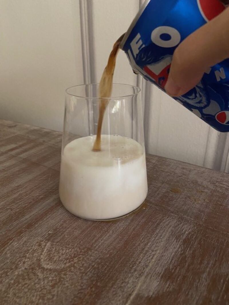 Add Pepsi to the milk, watching the white turn a pale coffee colour