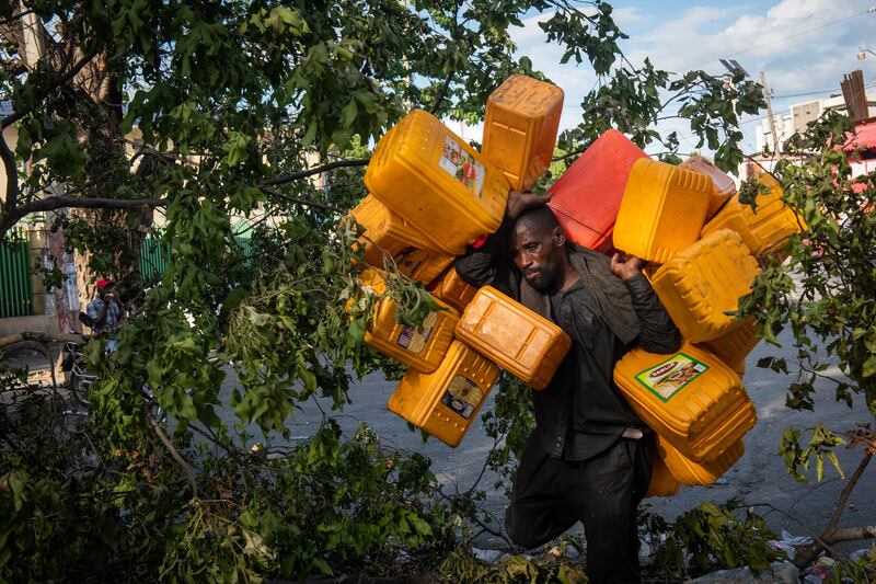 A man carries several buckets to stock up on fuel during the strike against the increase in fuel prices, in Port-au-Prince, Haiti. EPA
