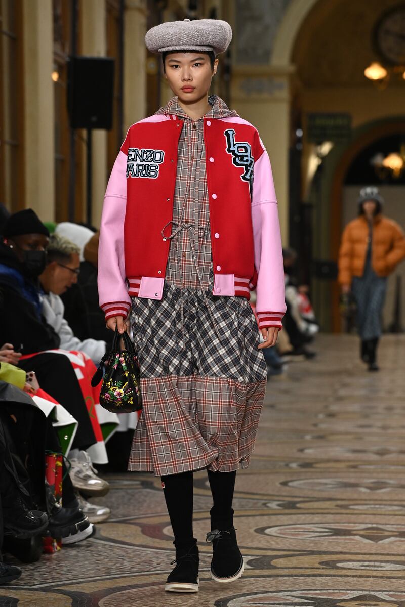 A dress in clashing checked fabrics is worn with a varsity jacket decorated with the date Kenzo first opened its doors in 1970.