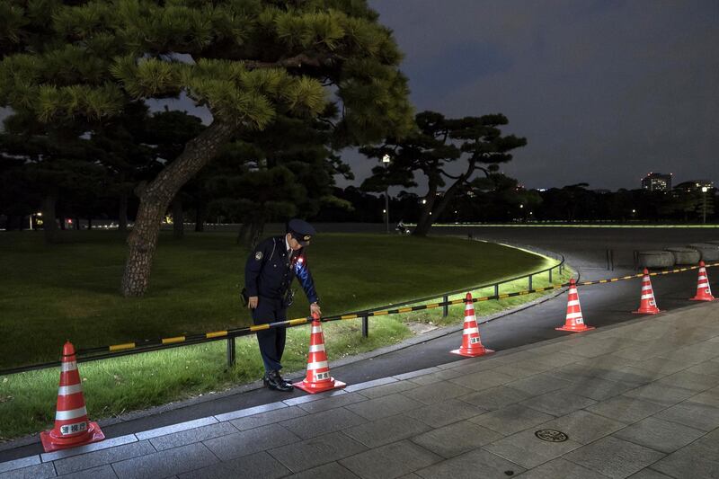 A police officer places a traffic cone outside the Imperial Palace at night as Japan prepares for the enthronement of Emperor Naruhito.  Getty