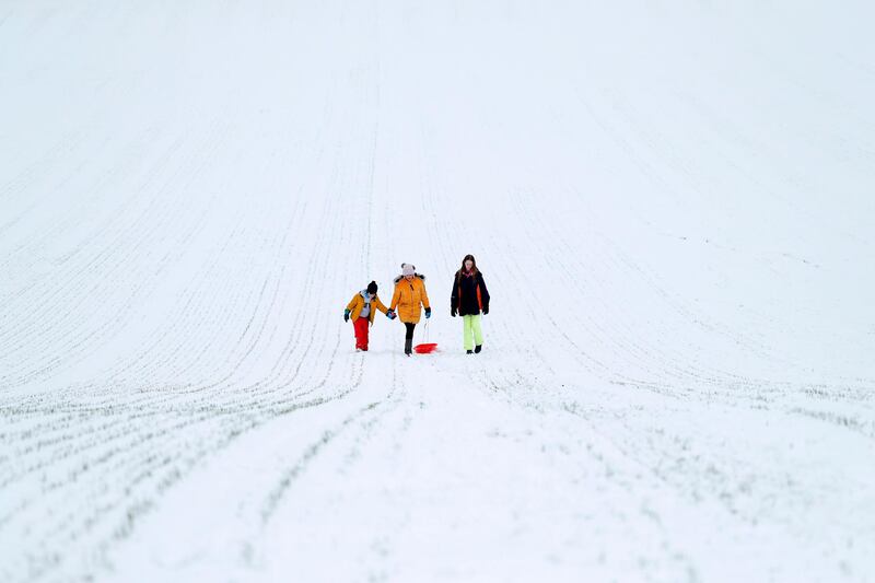 People make their way back up the hill after riding a sled down a snow-covered field beside St. Mary's Church after heavy snowfall in Hartley Wintney, west of London. AFP