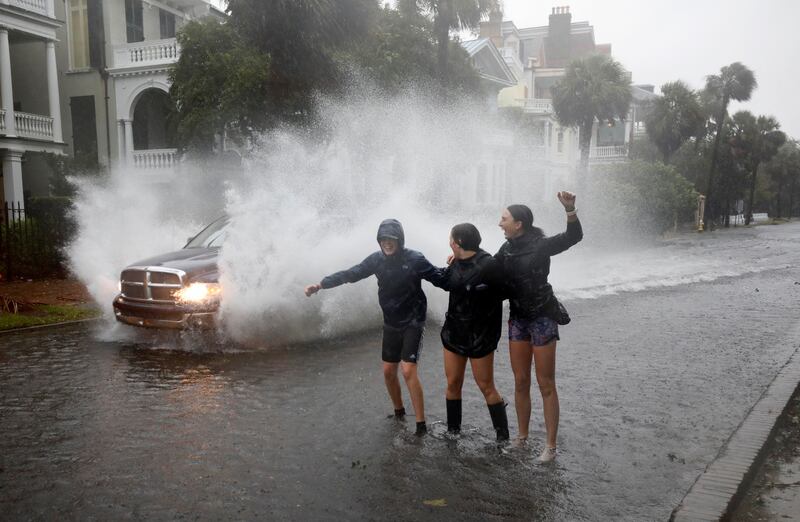 Young residents react as a truck sprays water while driving past them on a street flooded due to Hurricane Ian, in Charleston, South Carolina, US. Reuters