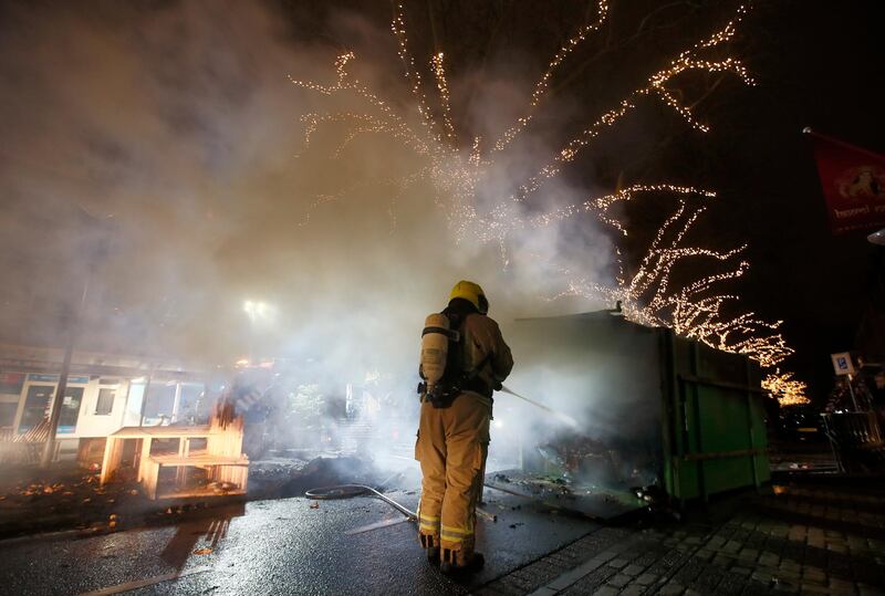 A firefighter extinguishes a container that was set alight during protests in Rotterdam. AP Photo