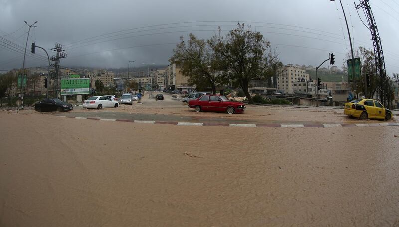 Palestinians drive their cars during a rain storm in Nablus. EPA