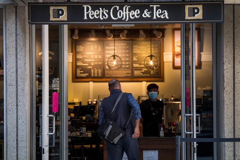 An employee wearing a protective mask takes an order from a customer at a Peet's Coffee & Tea store in San Francisco, California, U.S., on Wednesday, May 20, 2020. JAB Holdings NV, the investment fund backed by the billionaire Reimann family, plans to raise as much as 2 billion euros ($2.2 billion) by listing its coffee business, showing that the resilience of the beverage during the coronavirus pandemic could end up driving Europe's biggest stock-market debut in more than a year. Photographer: David Paul Morris/Bloomberg