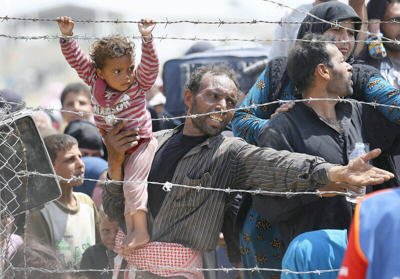 A Syrian refugee reacts as he waits behind border fences to cross into Turkey at Akcakale border gate in Sanliurfa province, Turkey, June 15, 2015. On Sunday, Turkish authorities reopened the border after a few days of closure, a security source said, adding that they expected as many as 10,000 people to come across. REUTERS/Umit Bektas TPX IMAGES OF THE DAY