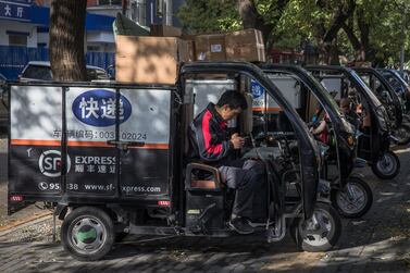 An employee sits in a a three-wheeled vehicle with packages loaded on top for delivery before Singles Day in Beijing, China. EPA