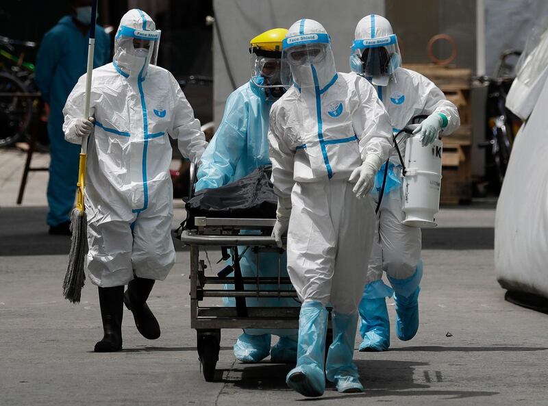 Health workers in protective suits transport a corpse at a hospital in Manila, Philippines. AP Photo