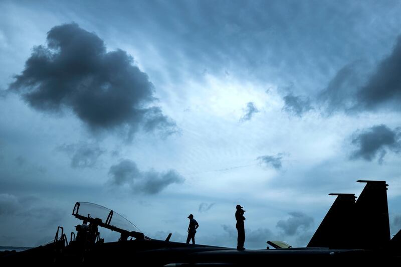 Republic of Singapore Air Force staff are silhouetted as they stand atop an F-15SG fighter jet during the Singapore Airshow. Yong Teck Lim / AP Photo