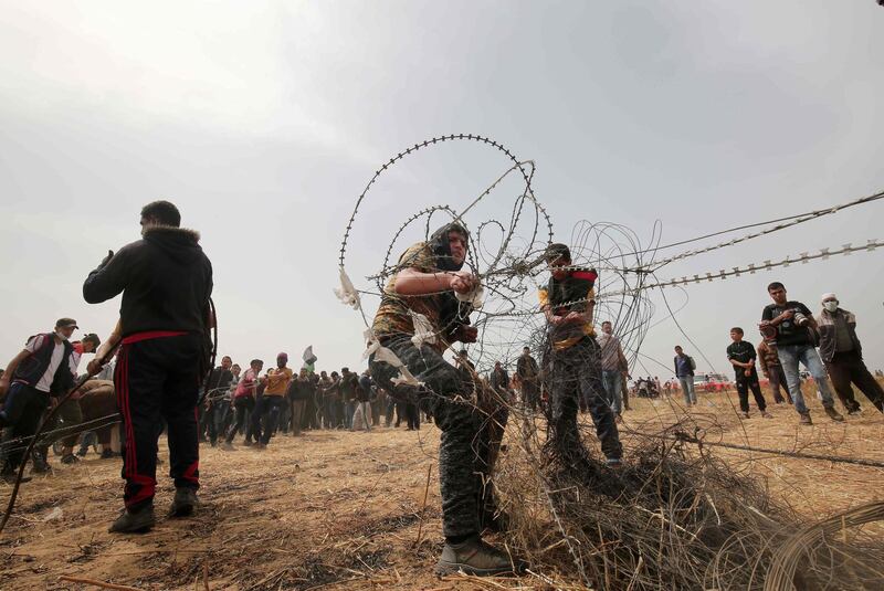 TOPSHOT - Palestinian protestors pull barbed wire from the border fence with Israel, in Rafah in southern Gaza Strip on April 20, 2018.
A Palestinian was shot dead by Israeli forces in the northern Gaza Strip on Friday, medical sources said, as demonstrations entered their fourth week along the Gaza-Israel border. / AFP PHOTO / SAID KHATIB