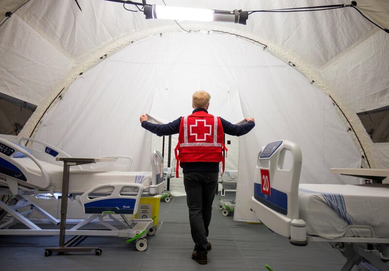 A volunteer with the Red Cross shows a doorway between beds in a mobile hospital set up in partnership with the Canadian Red Cross in the Jacques-Lemaire Arena to help care for patients with the coronavirus disease (COVID-19) from long-term centres (CHSLDs), in Montreal, Quebec, Canada. REUTERS