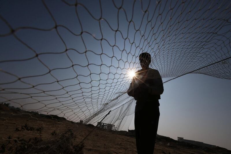 A Palestinian sets up a net to catch songbirds at the site of Gaza destroyed airport, in Rafah. Rueters