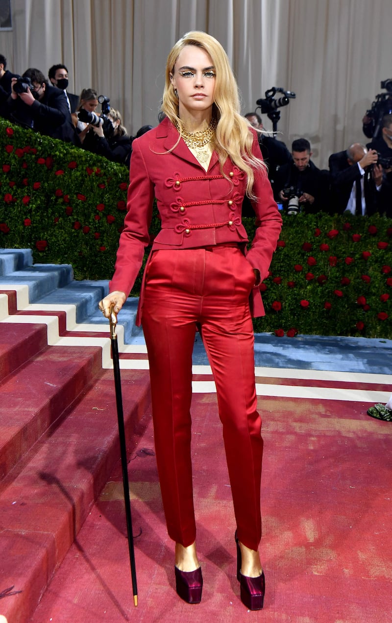 Cara Delevingne, wearing a red suit. AFP