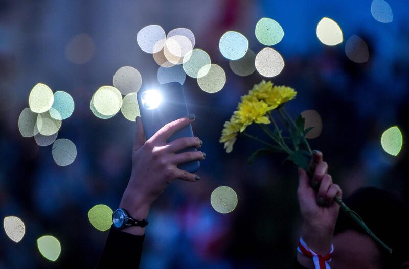 Two women hold a mobile phone and flowers during a protest in Minsk against police violence during recent rallies of opposition supporters, who accuse Alexander Lukashenko of falsifying the polls in the presidential election.  AFP