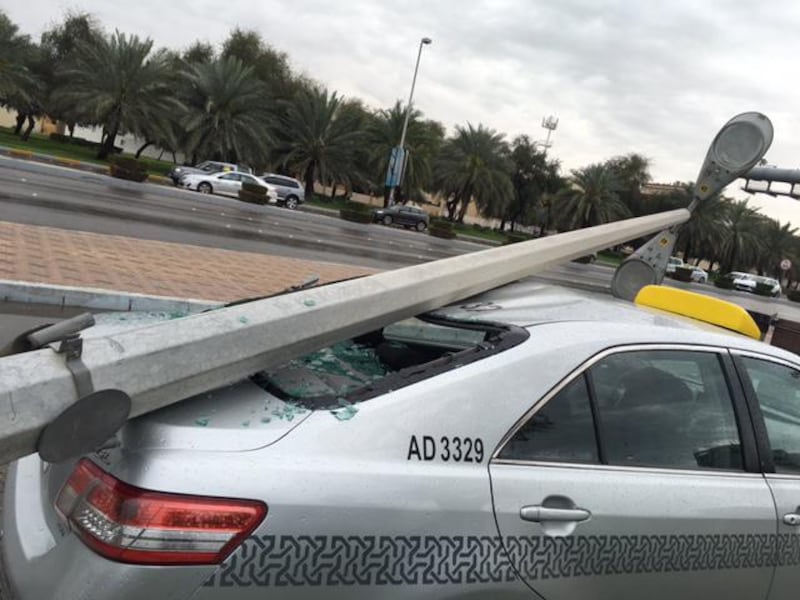 A lappost falls onto a taxi at the junction of Hazza bin Zayed Street and Mubarak bin Mohammed Street near the Shaheen Supermarket and Khalidiya Police Station. Ramona Ruiz / The National