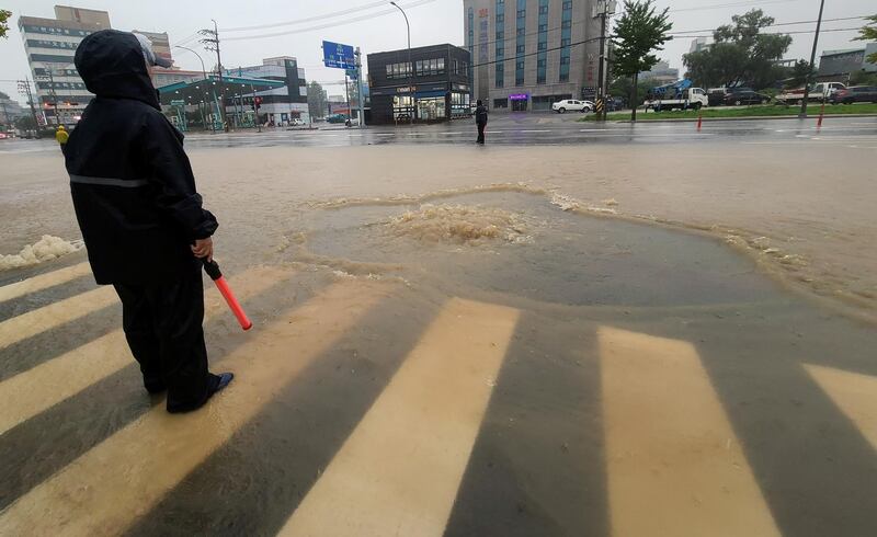 A man diverts traffic on a submerged road caused by typhoon Haishen in Sokcho, South Korea. Reuters