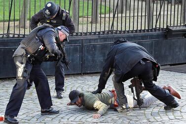 Armed police restrain a man inside the grounds of the Houses of Parliament in London. Reuters