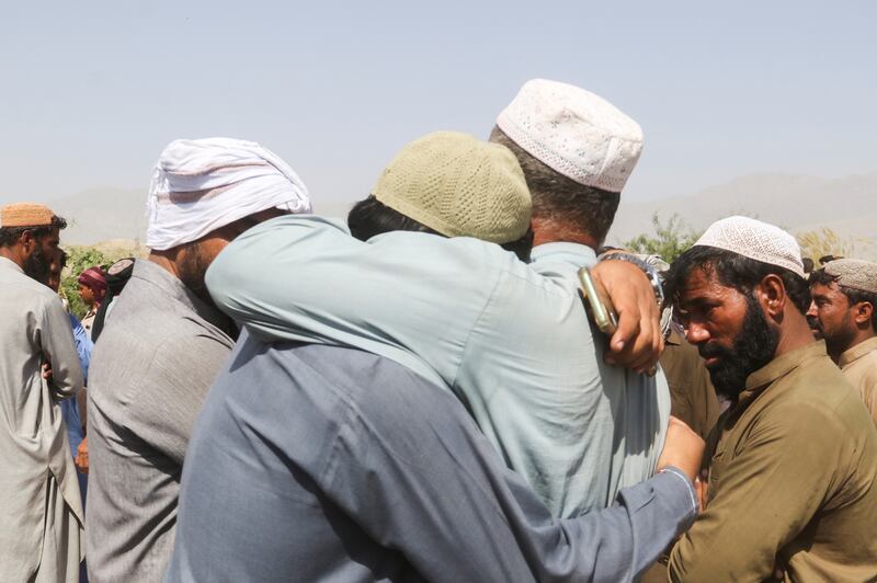 Men comfort each other as they mourn the death of relatives during a funeral in quake-hit Balochistan, Pakistan. Reuters
