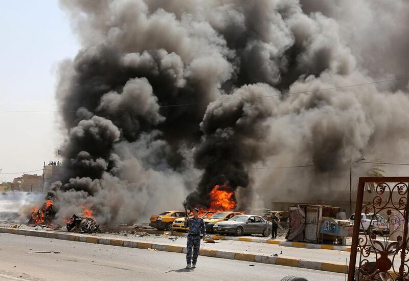 Policemen stand near burning vehicles moments after one in a series of bombs hit the Shiite stronghold of Sadr City in Baghdadon on May 13, 2014. Karim Kadim / AP Photo