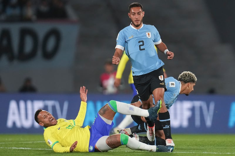 Neymar falls while fighting for the ball with Uruguay's Sebastian Caceres. AP