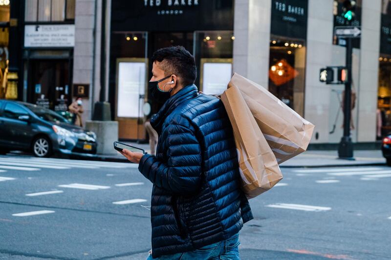 A pedestrian wearing a protective mask carries shopping bags across Fifth Avenue in New York, U.S., on Friday, Nov. 27, 2020. With sparse crowds and none of the stampedes of holidays past, some retail watchers started to refer to Black Friday as Blase Friday instead -- and that was even before the virus hit. Photographer: Gabriela Bhaskar/Bloomberg