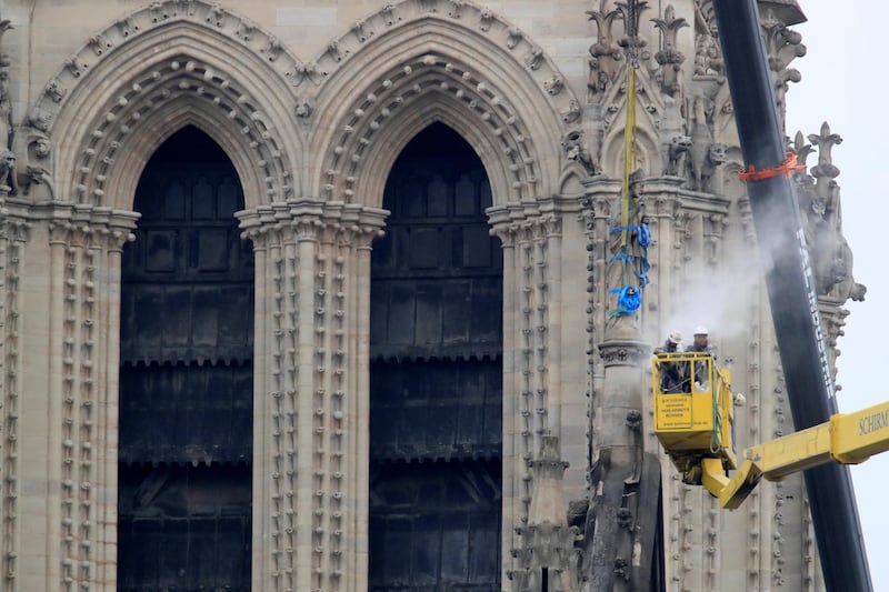Men work on a statue at Notre-Dame Cathedral after a massive fire devastated large parts of the gothic structure in Paris. Reuters