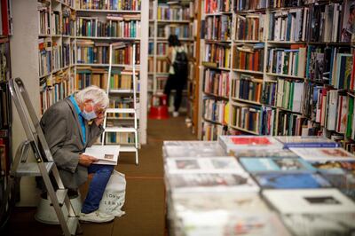 A man wearing a protective face mask browses books in Henry Pordes secondhand book shop in central London on June 15, 2020, as some non-essential retailers reopen from their coronavirus shutdown. - Various stores and outdoor attractions in England are set to open Monday for the first time in nearly three months, as the government continues to ease its coronavirus lockdown. (Photo by Tolga AKMEN / AFP)