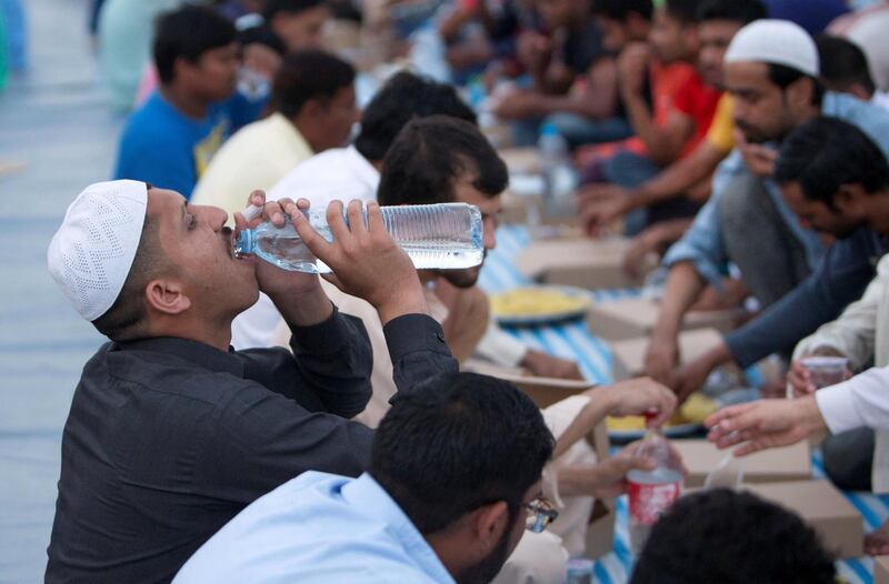 DUBAI, UNITED ARAB EMIRATES -  Workers breaking their fast. Dubai Police join hands with Berkeley Assets to serve up Iftar dinner to mark Laylatul Qadr for 10,000 labourers with seating for 5,000 and another 5,000 laborers will go home with meal boxes in Al Muhaisnah, Dubai.  Ruel Pableo for The National