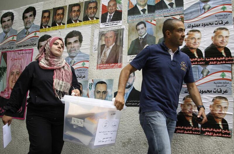 Lebanese government election officials walk past a wall on which posters of Lebanese candidates running in the country's municipal election are pasted. Mohamed Azakir / Reuters