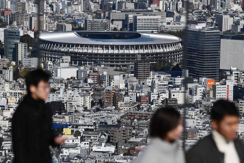 People at a viewing area look out at the completed Tokyo 2020 Olympic Games stadium. AFP
