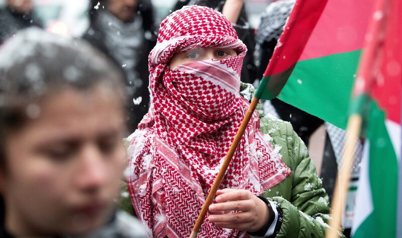 A demonstrator covering her face with a keffiyeh during a rally in support of the Palestinian people, in Sarajevo, Bosnia and Herzegovina. EPA