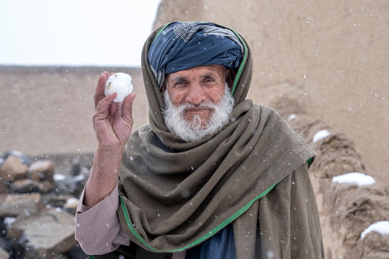 An old Afghan man holds a snowball during snowfall, on the outskirts of Kabul, Afghanistan, Thursday, Dec.  29, 2022. (AP Photo / Ebrahim Noroozi)