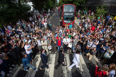 Beatles lookalikes are joined by thousands of fans gathered to walk across the Abbey Road zebra crossing, on the 50th anniversary of British pop musicians The Beatles doing it for the cover of their album 'Abbey Road' in St Johns Wood in London, Thursday, Aug. 8, 2019. They aimed to cross 50 years to the minute since the 'Fab Four' were photographed for the album.(Dominic Lipinski/PA via AP)