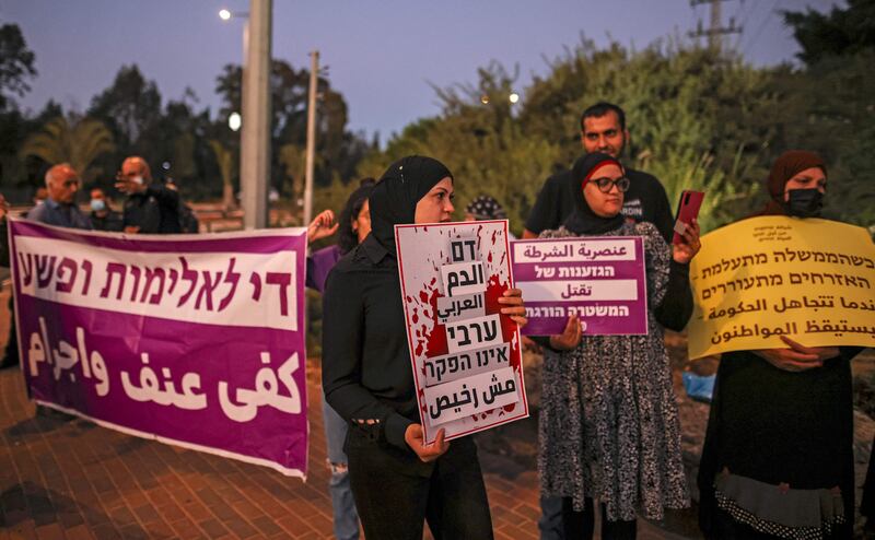 Demonstrators hold up signs reading in Arabic and Hebrew (R to L) "when the government ignores, the citizen awakens", "police racism kills", "Arab blood is not cheap", "enough violence and criminality" during a protest by Arab Israelis and activists against the government's insufficient action towards rising violence levels within the Arab community, outside the home of Public Security Minister Omer Bar-Lev in the northern Israeli town of Kokhav Yair. AFP