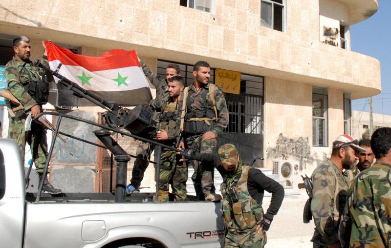 Syrian soldiers hold a flag in a street of Hteitit Al Turkman, a key town southeast of Damascus, after capturing it. Their weapons could be provided from several weekly flights from Tehran. Sana via AP



