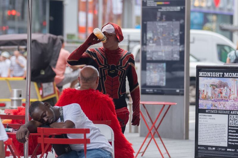 A costumed spiderman drinks during a heat wave in New York. Bloomberg