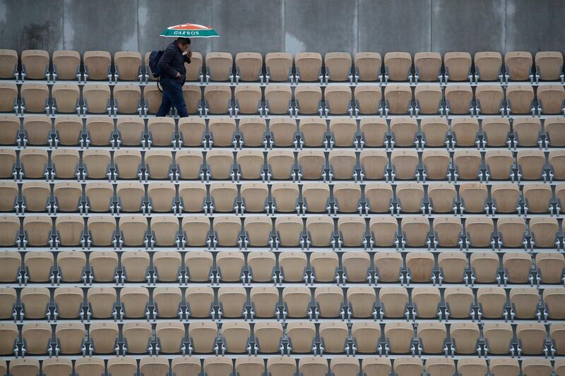 A spectator with an umbrella walks away after all matches of the French Open tennis tournament were cancelled due to rain at the Roland Garros stadium in Paris. AP