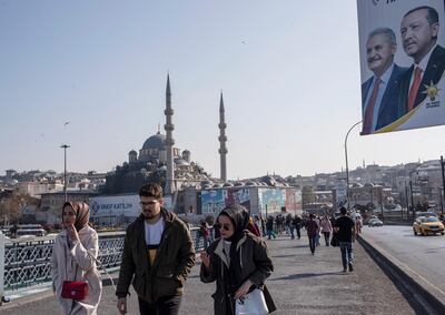 epa07487079 People walk on Galata Bridge as they pass in front of a picture of Turkish President Recep Tayyip Erdogan and AKP candidate for Istanbul Mayor Binali Yildirim, in Istanbul, Turkey, 05 April 2019. According to preliminary results, CHP candidate for Istanbul mayor, Ekrem Imamoglu, beat the AKP candidate Binali Yildirim, by 25,000 votes in what was viewed as a blow to President Recep Tayyip Erdogan's grip on power, as the ruling party, an Islamist conservative outfit, also lost the capital, Ankara.  EPA/SEDAT SUNA