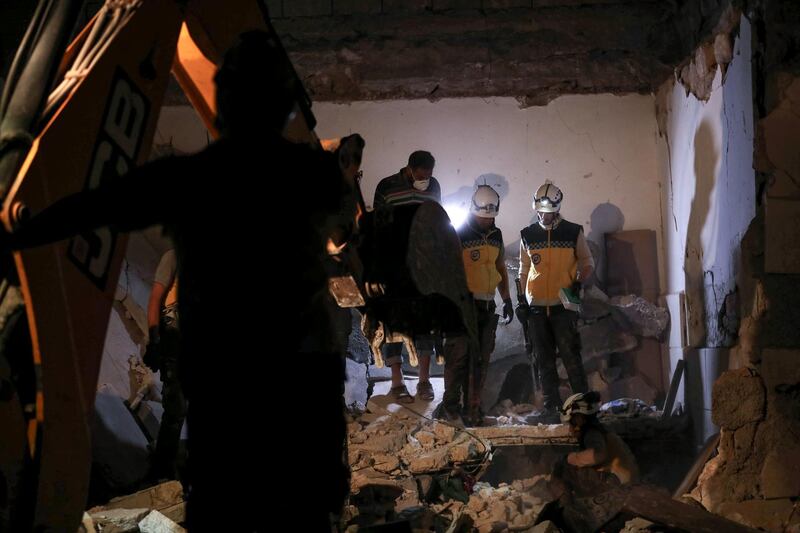 Members of the Syrian Civil Defence, also known as the "White Helmets", clear debris while searching for bodies or survivors in a collapsed building following a reported government air strike in the village of Saraqib in Syria's northwestern Idlib province.  AFP