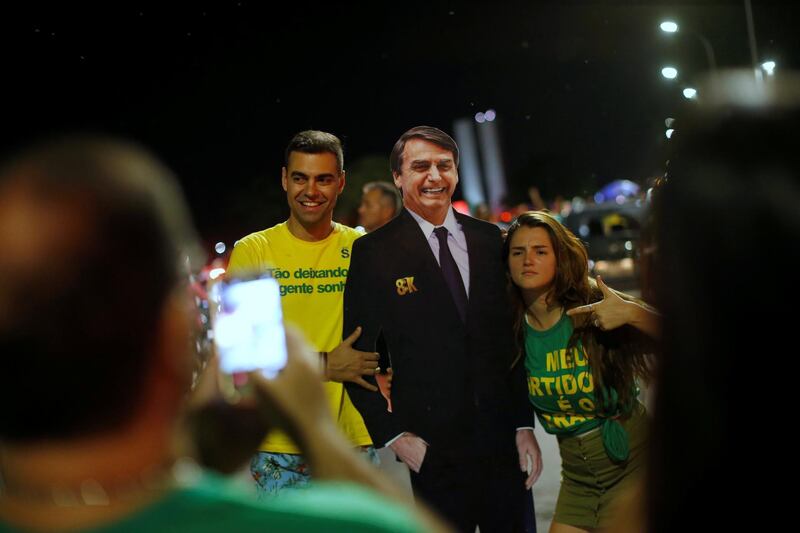 Supporters of Jair Bolsonaro pose with a cardboard cutout of Bolsonaro, in Brasilia. Reuters