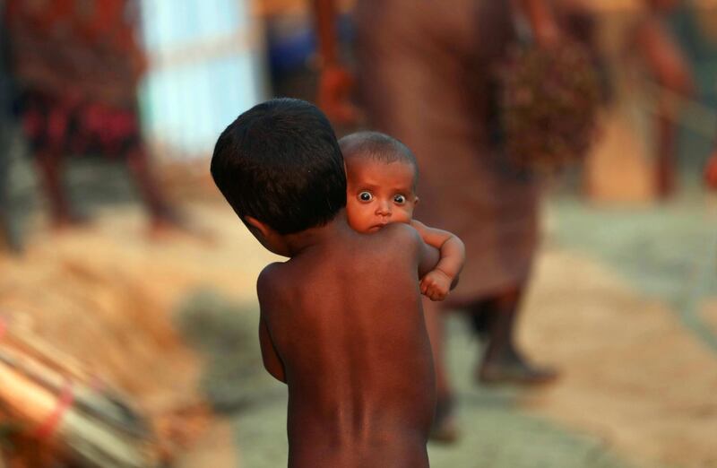 A Rohingya refugee child carries an infant at a refugee camp in Palang Khali near Cox's Bazar, Bangladesh, October 4, 2017. REUTERS/Mohammad Ponir Hossain - RC1A21B71950