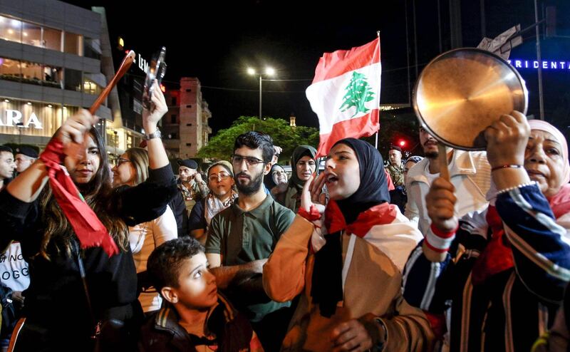 Protesters chant slogans, bang pot covers, and wave a Lebanese national flag during an anti-government demonstration in the southern Lebanese city of Sidon on December 1, 2019.  / AFP / Mahmoud ZAYYAT
