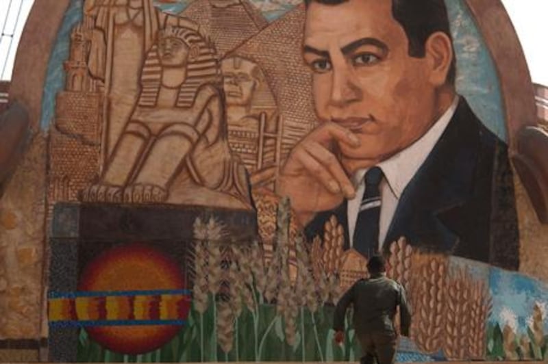 An Egyptian soldier walks up the steps next to a stone mural with an image depicting former Egyptian President Hosni Mubarak on the outskirts of Cairo, Egypt, Tuesday Feb. 15, 2011.  On Tuesday, the Armed Forces Supreme Council said a panel of experts would craft constitutional amendments to allow free elections later this year. (AP Photo/Emilio Morenatti)