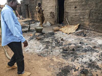 Officials and residents stand near ashes on June 11, 2019 in the Dogon village of Sobane-Kou, near Sangha, after an attack that killed over 100 ethnic Dogon on June 9, 2019 evening. The attack came less than three months after nearly 160 members of the Fulani ethnic group were slaughtered by a group identified as Dogon. / AFP / STRINGER
