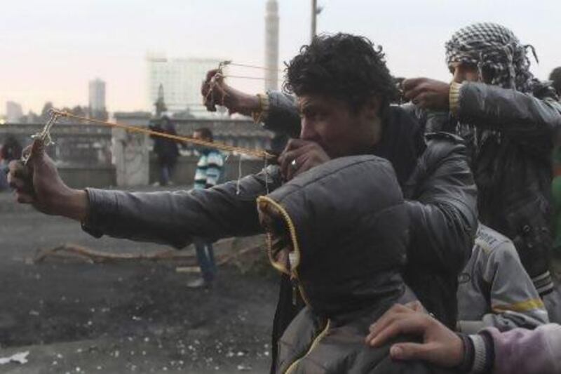 Protesters use slingshots to launch stones at riot police during clashes near Qasr el-Nil bridge, in Cairo.