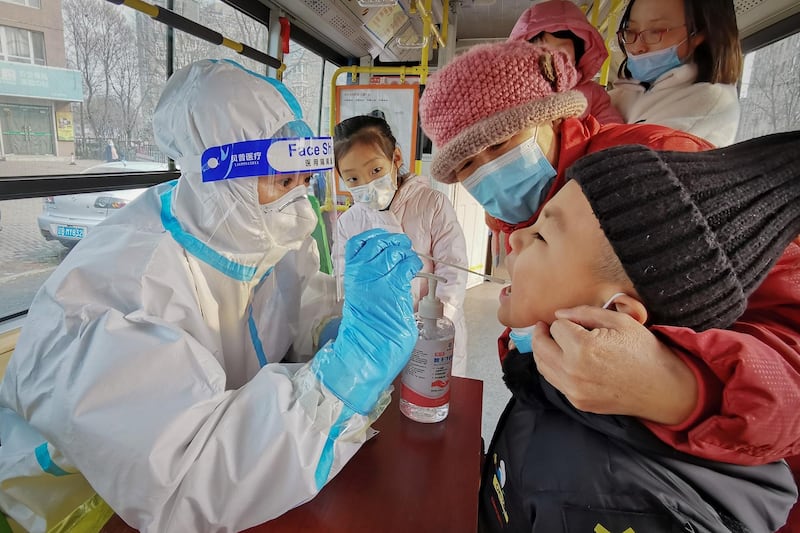 A health worker in a protective suit takes a swab from a child to test for the Covid-19 coronavirus as the city carries out a mass testing programme after new confirmed cases were found in Dalian, in northeastern China's Liaoning province. AFP