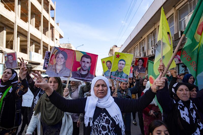 Syrian Kurds show pictures of people killed during conflict, as they protest against Turkish threats in the city of Qamishli on November 27. AFP