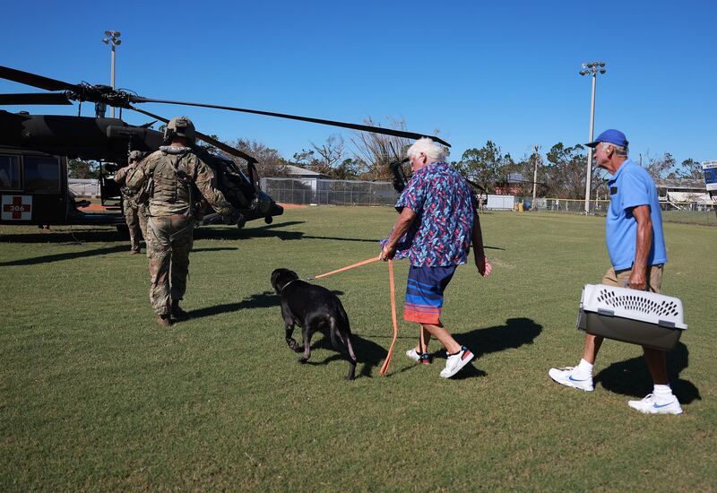 Tom O'Sullivan his dog Jack, and Harry Marquard prepare to be flown off the island in a Florida Army National Guard helicopter. Getty  / AFP